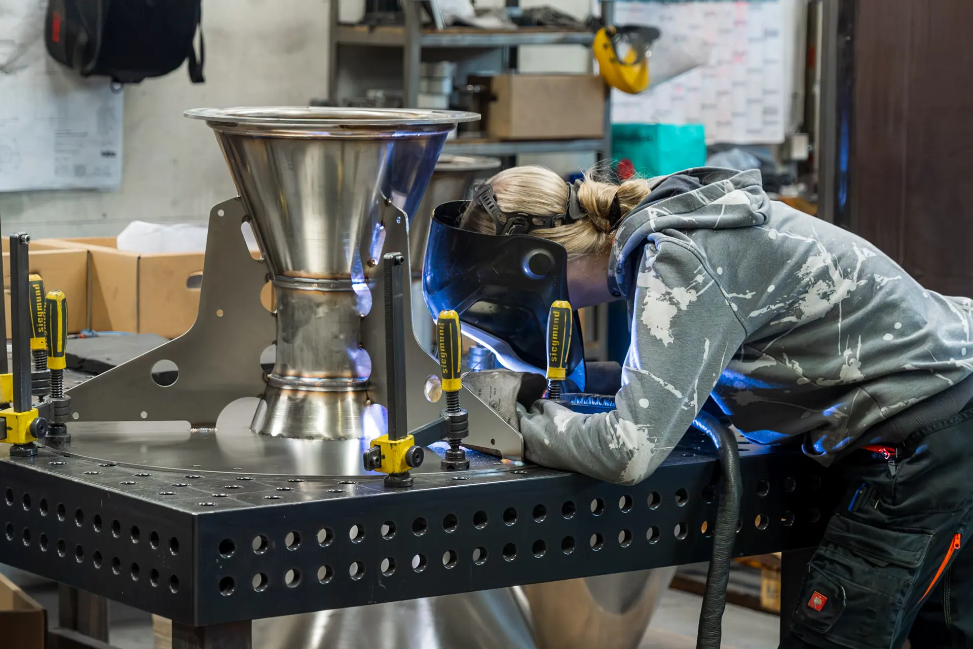 Person schweißt Metall in Werkstatt.