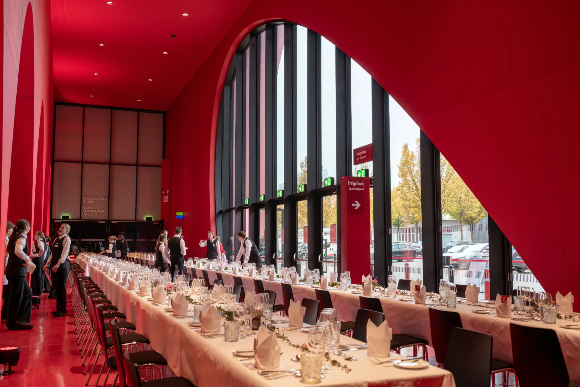 Langer roter Raum mit gedeckten Tischen.