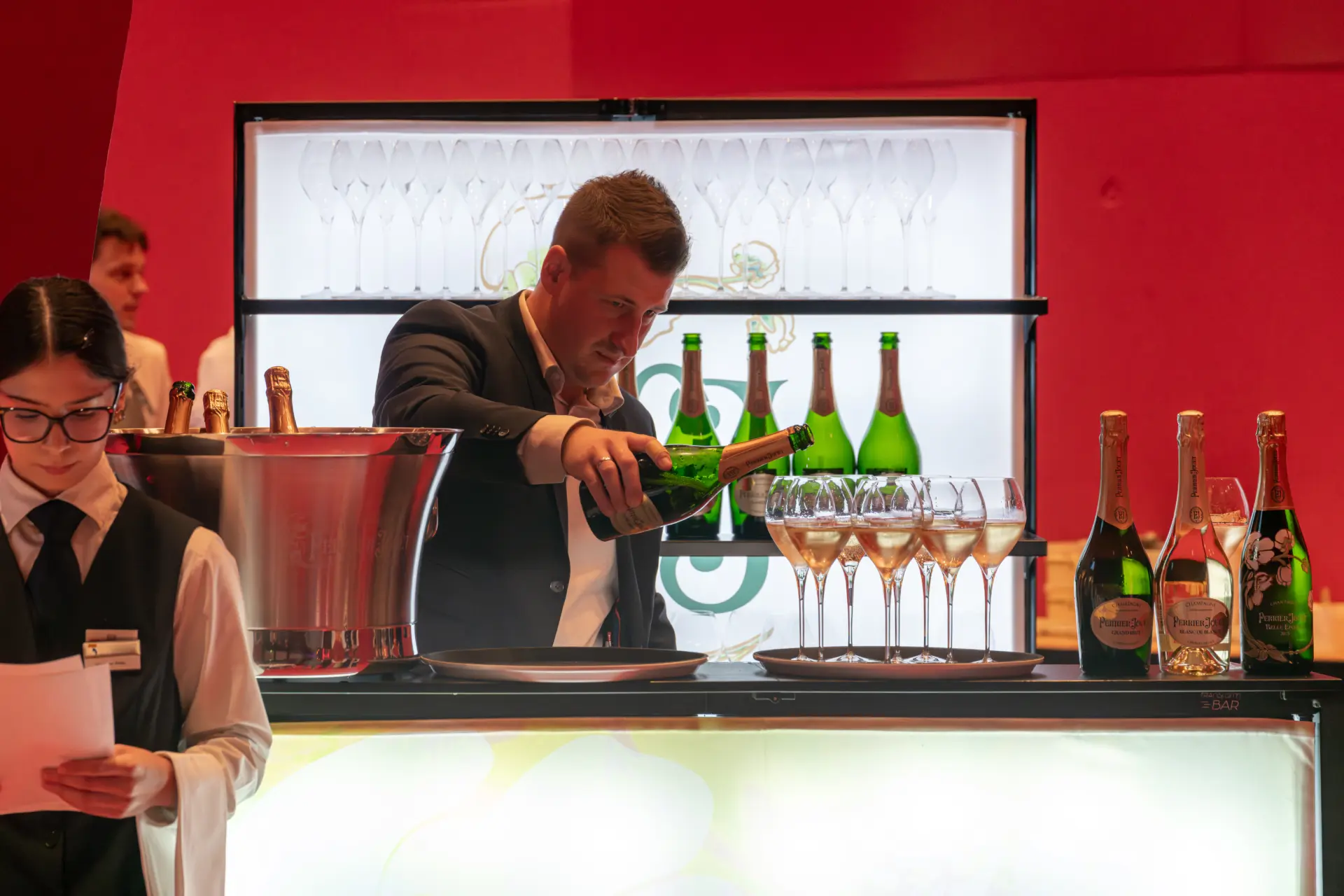 Barkeeper schenkt Champagner in Gläser ein.