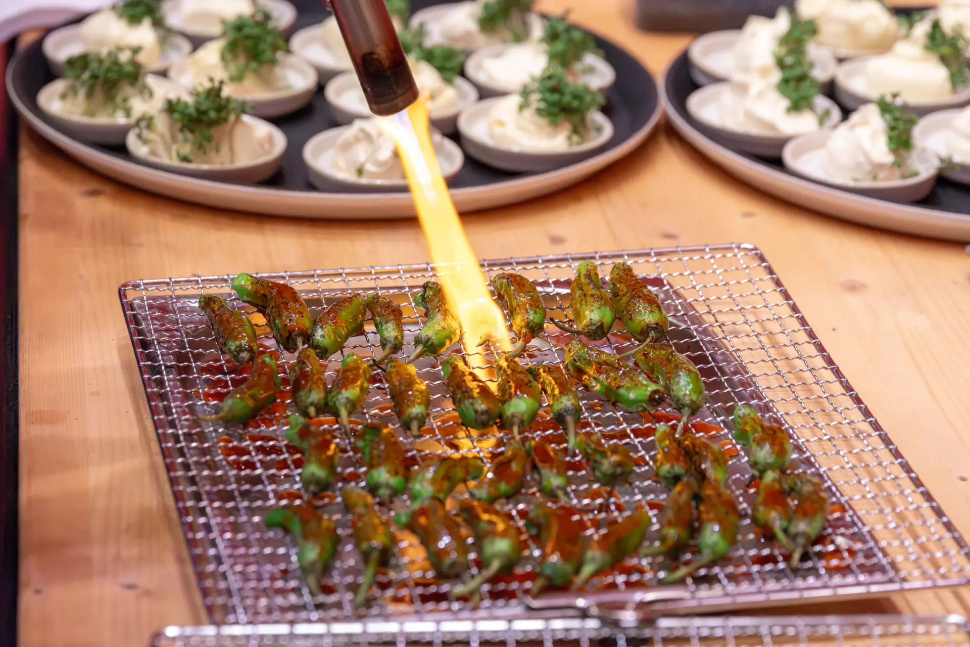 Gebratene Chilis mit Flambierbrenner auf Gitter.