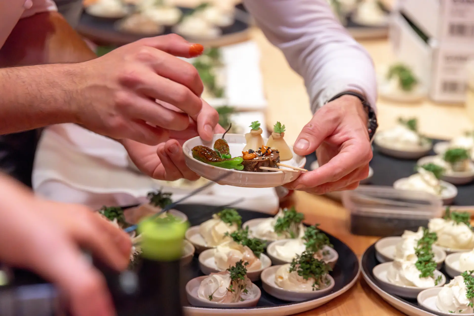 Personen richten kunstvolle Speisen auf Tellern an.