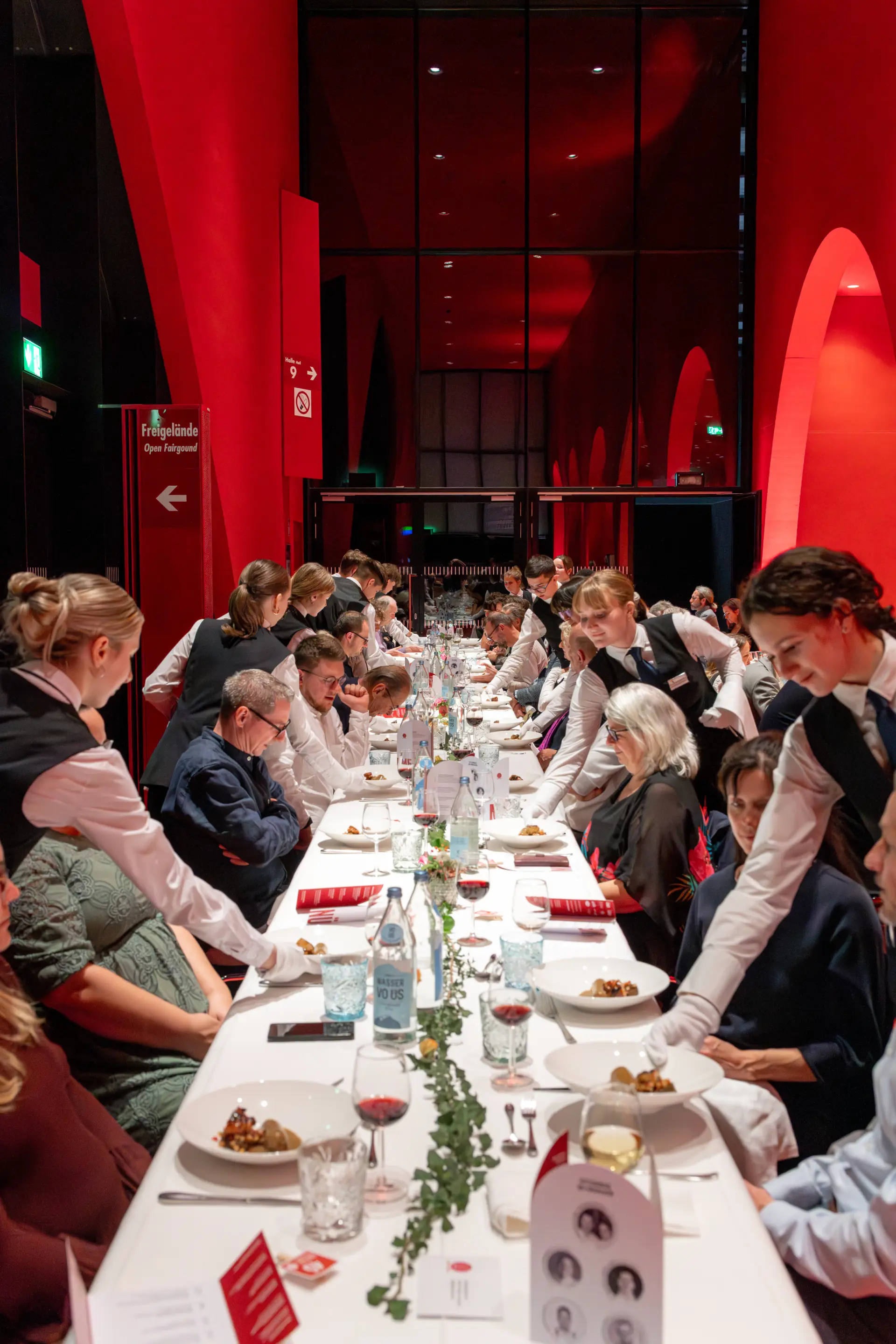 Servicepersonal serviert Essen bei einem Bankett in rotem Raum.