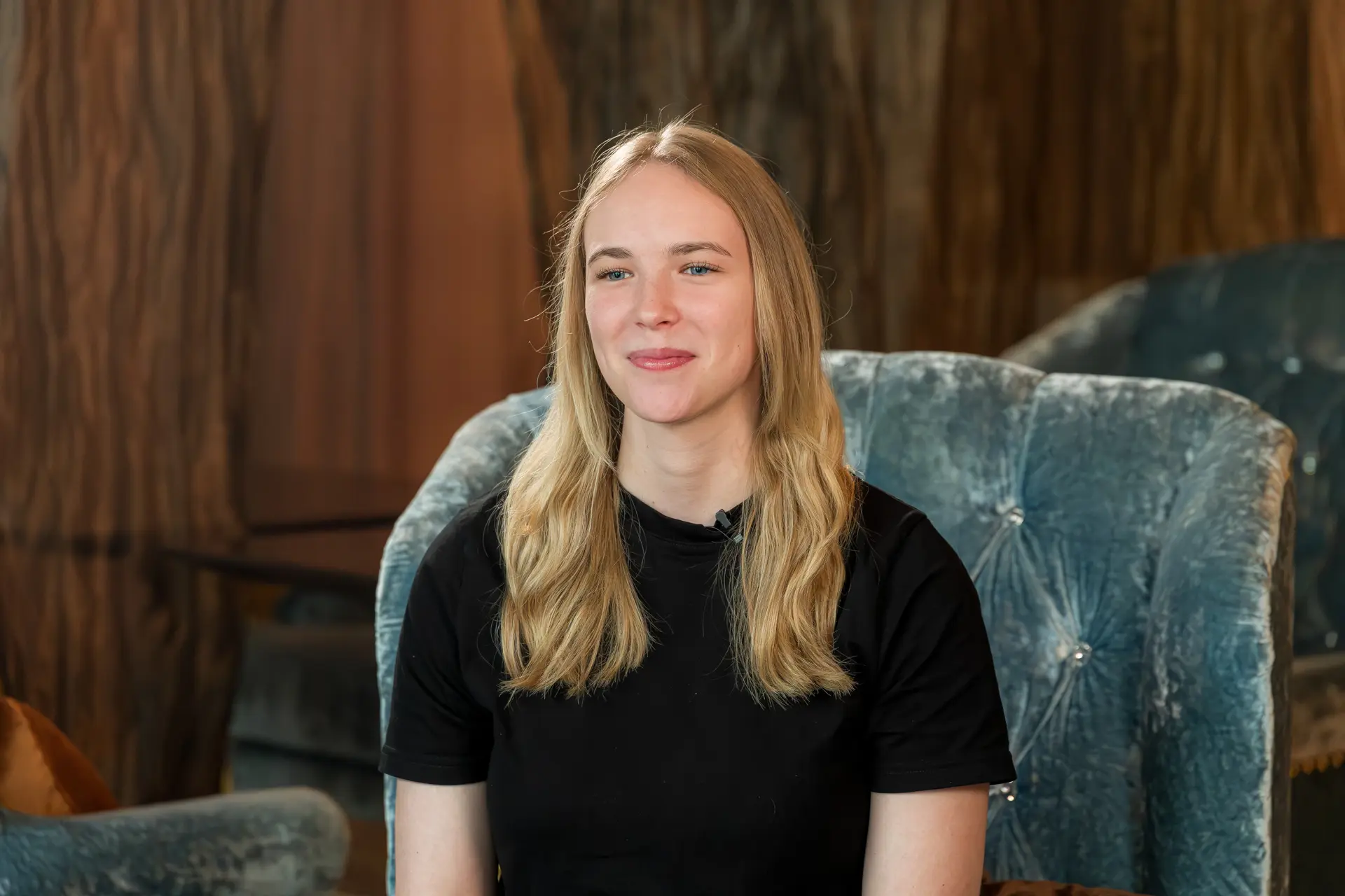 Frau lächelt auf blauem Sessel