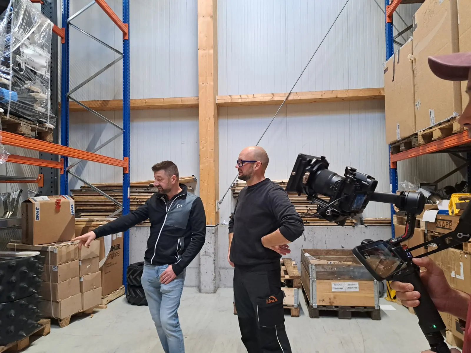 Zwei Männer im Lager, eine Kamera filmt