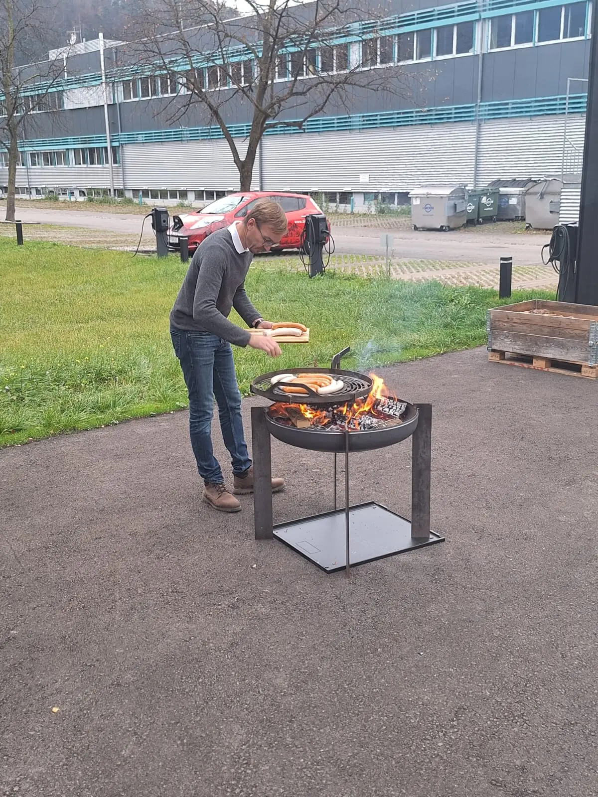 Mann grillt Würstchen auf offenem Feuer.