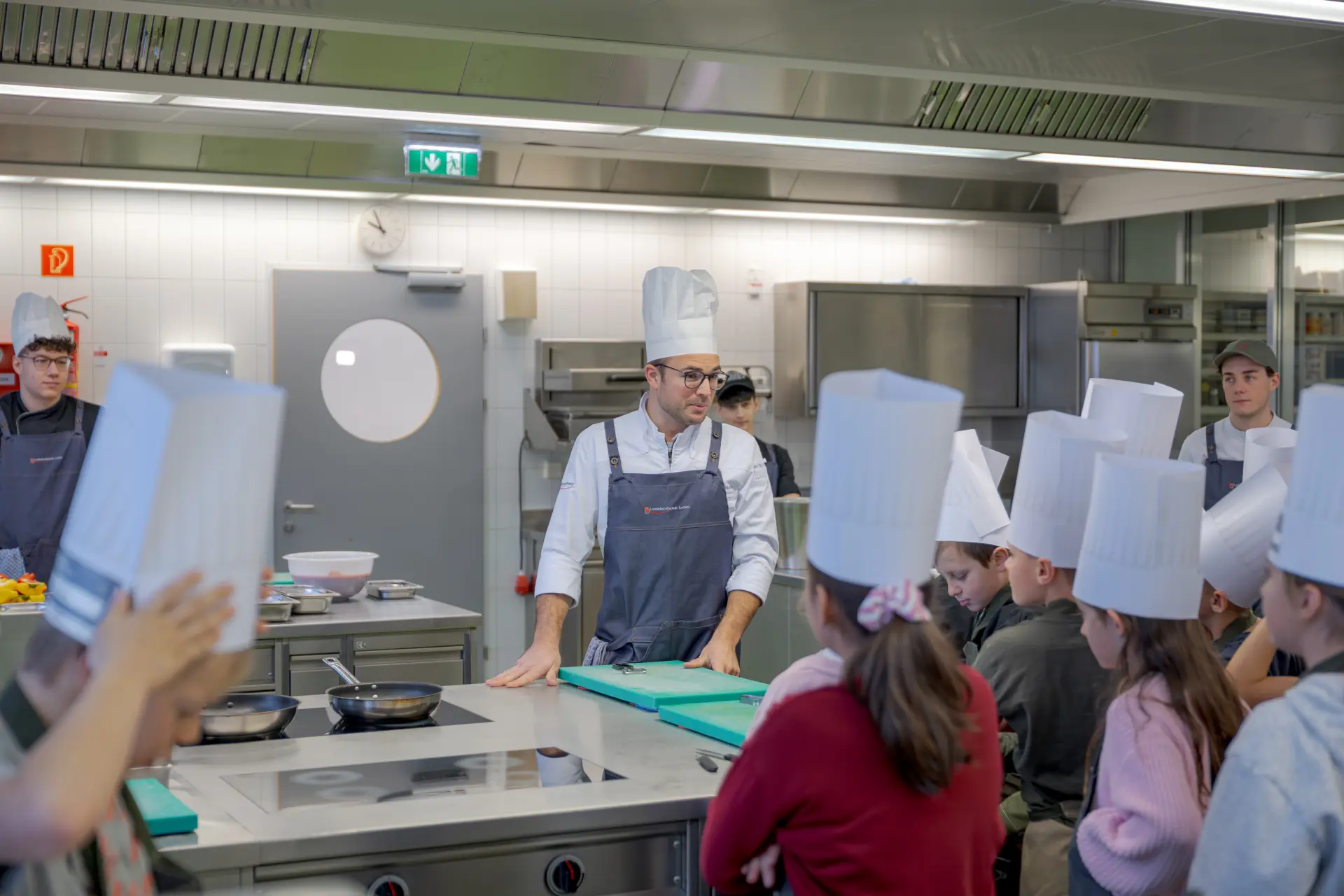 Koch unterrichtet Schüler in Küche.