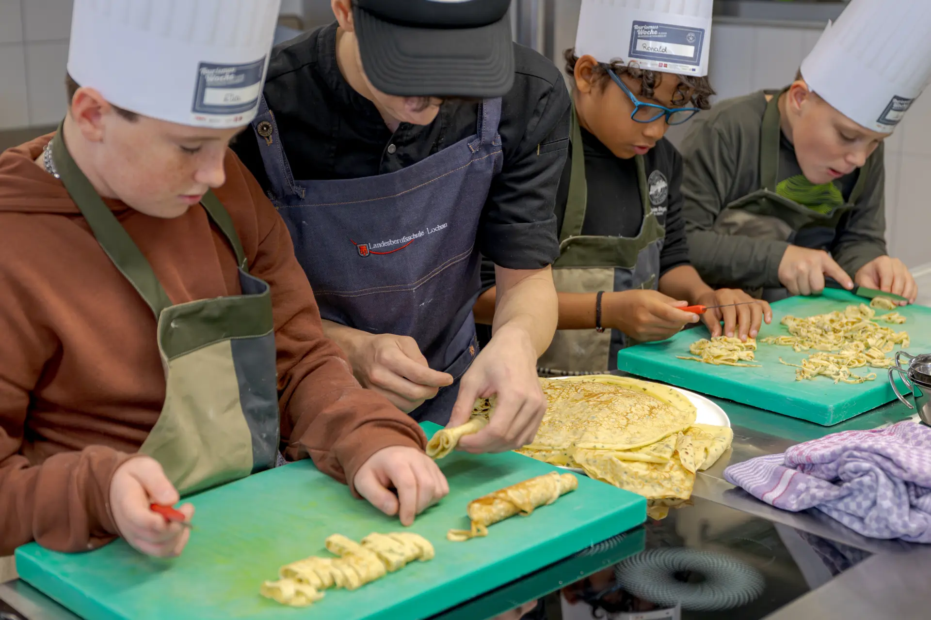 Kinder schneiden Pfannkuchen in einer Kochschule.