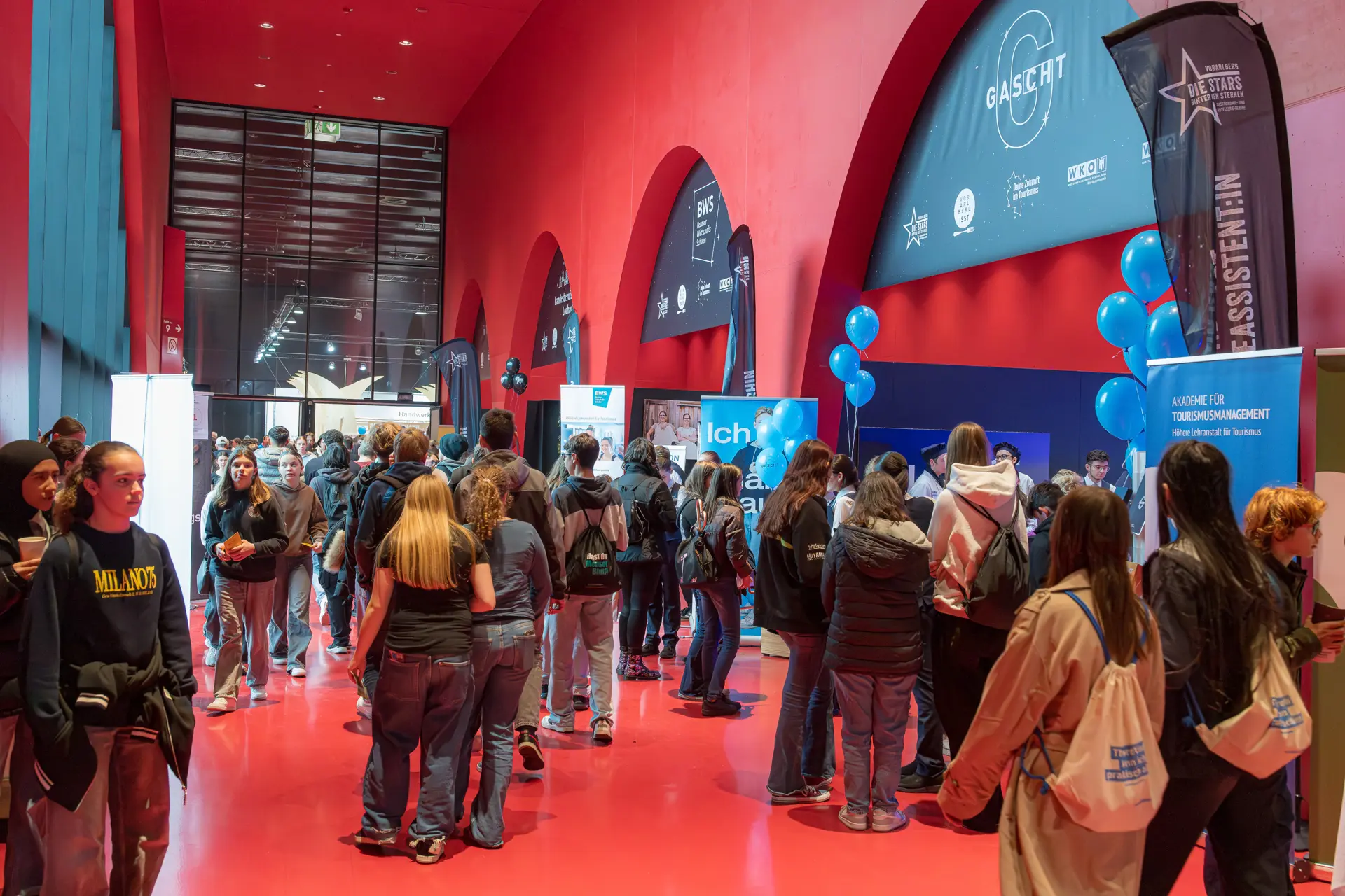 Menschenmenge auf einer Messe in rotem Raum.
