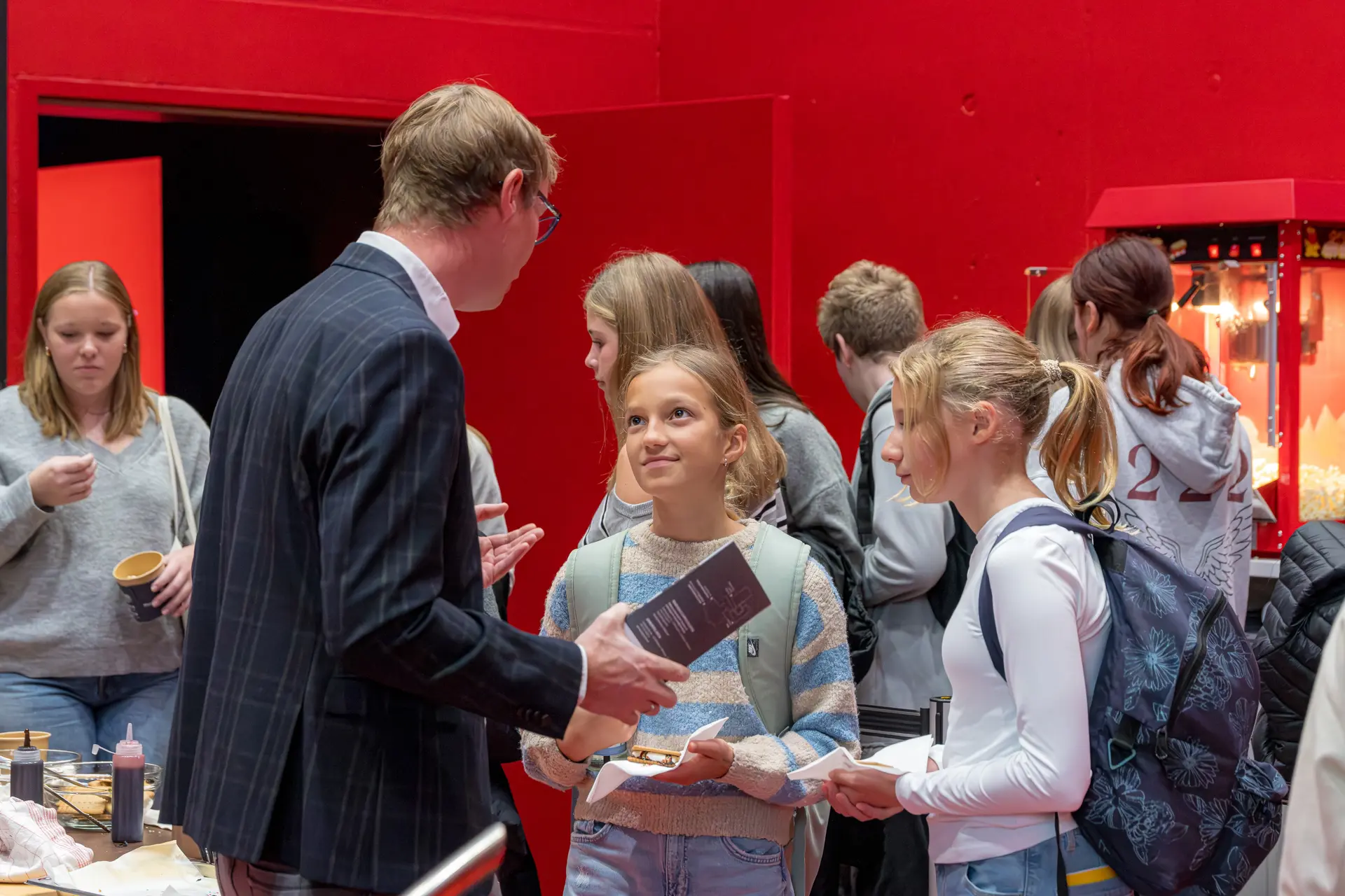 Person spricht mit Jugendlichen vor roter Wand.