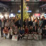 Gruppenfoto vor beleuchtetem Weihnachtsbaum in Geschäft.