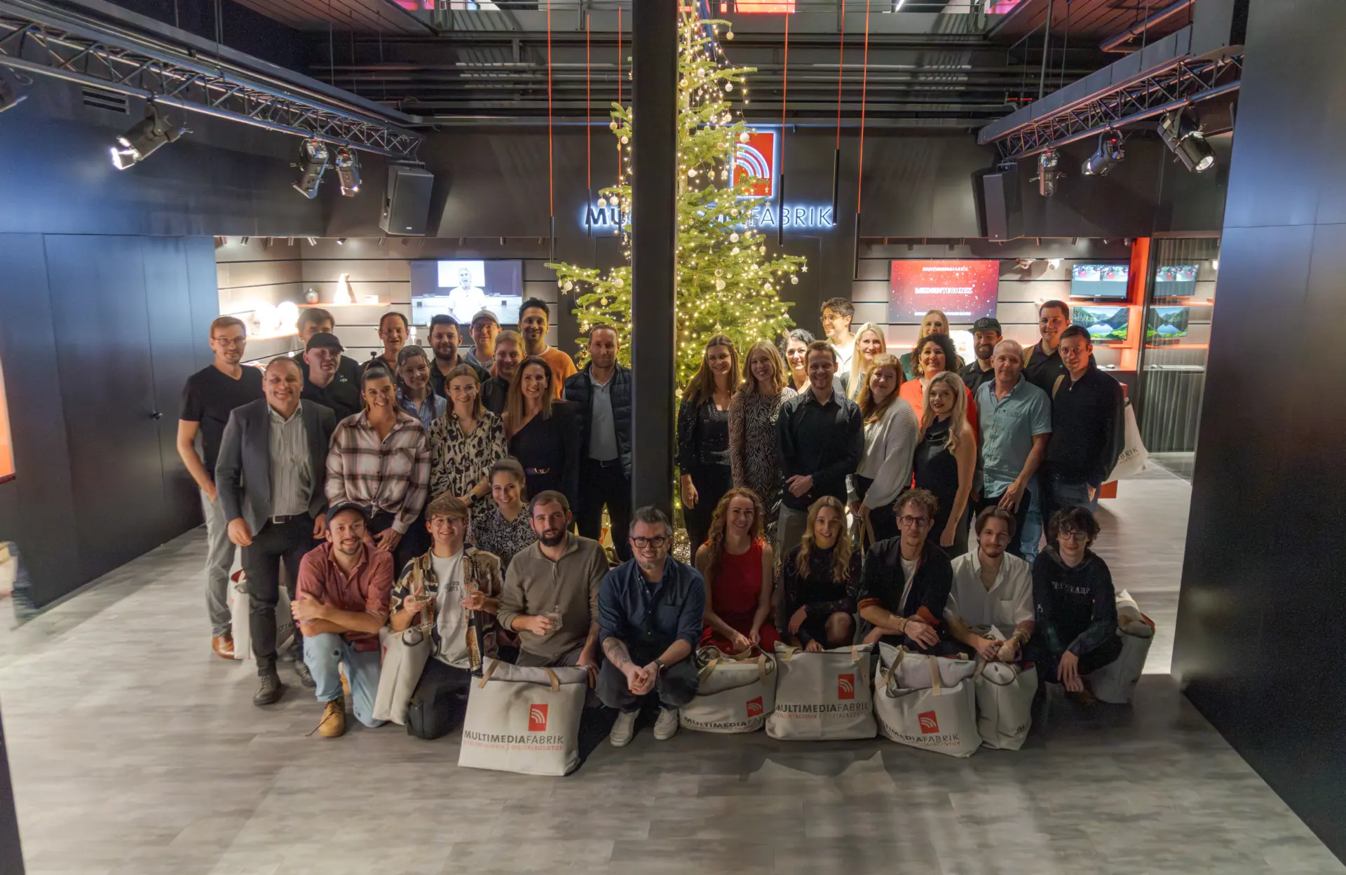 Gruppenfoto vor beleuchtetem Weihnachtsbaum in Geschäft.