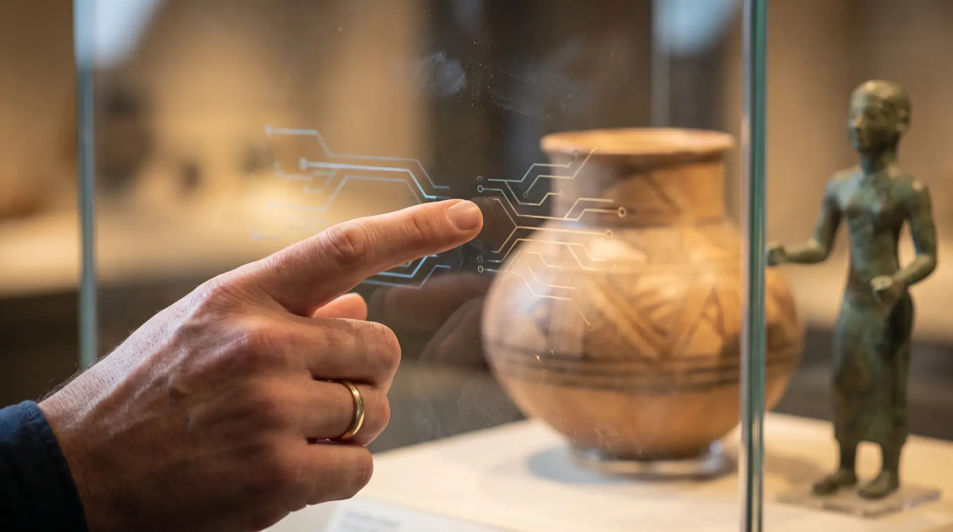 Hand wischt über das transparente Touch-Glas einer Museumsvitrine mit leuchtenden Interface-Linien