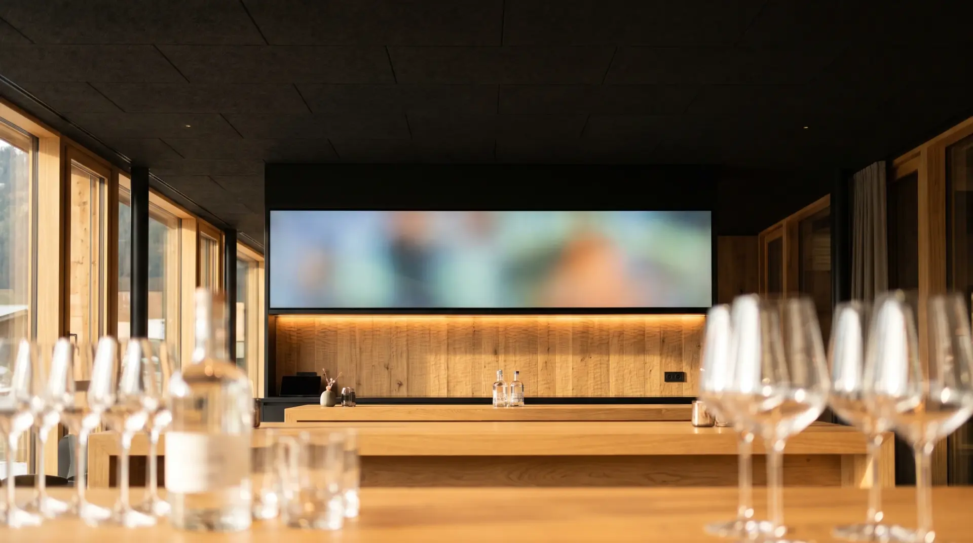 Bar-Theke eines modernen Restaurants im Abendlicht mit querformatigem Display über dem Rückbuffet