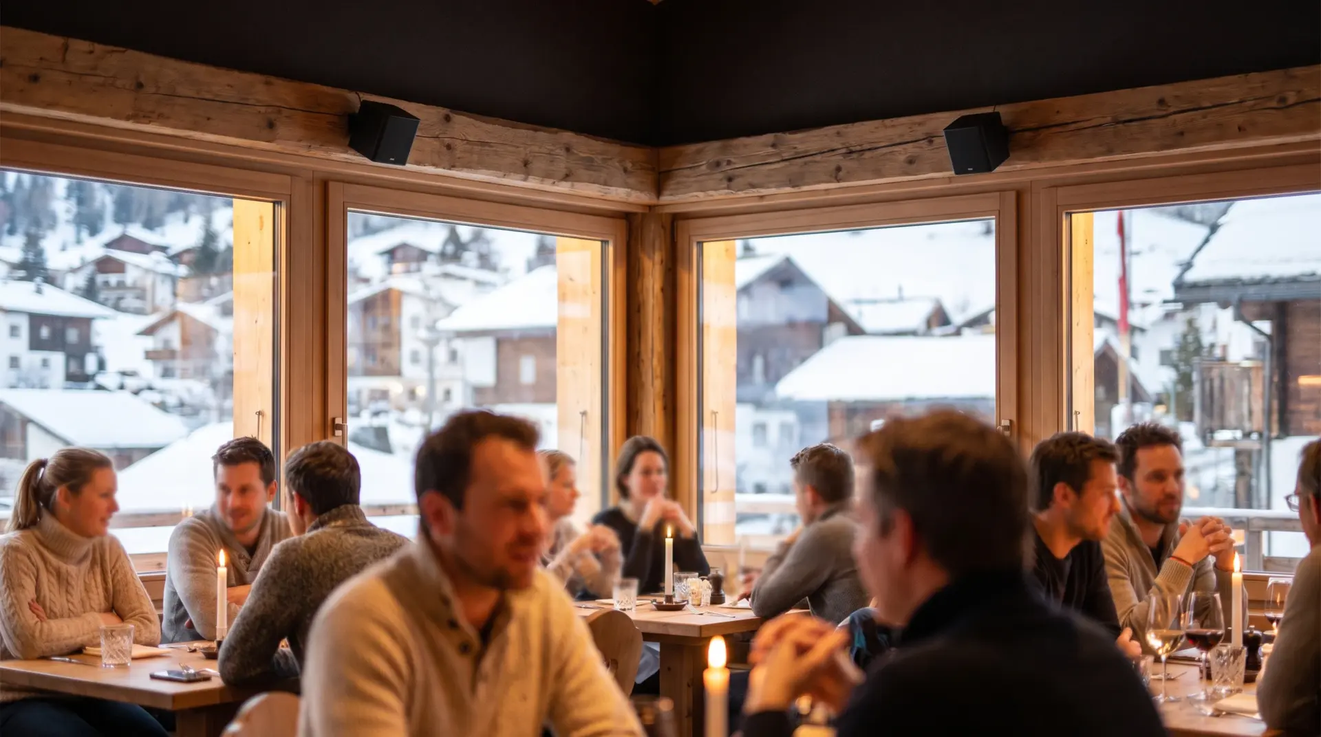 Gäste im warm beleuchteten Restaurant am Abend, dezenter Einbau-Lautsprecher an der Wand