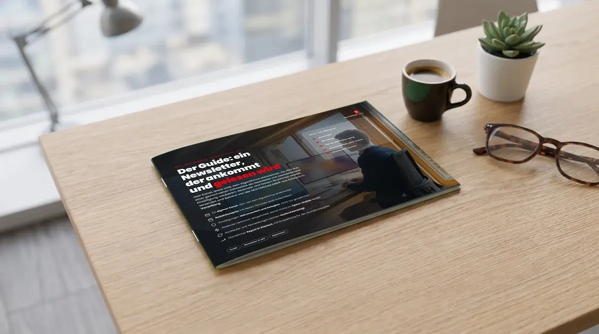 „Der Guide: ein Newsletter, der ankommt und gelesen wird“ der MULTIMEDIAFABRIK auf einem hellen Schreibtisch