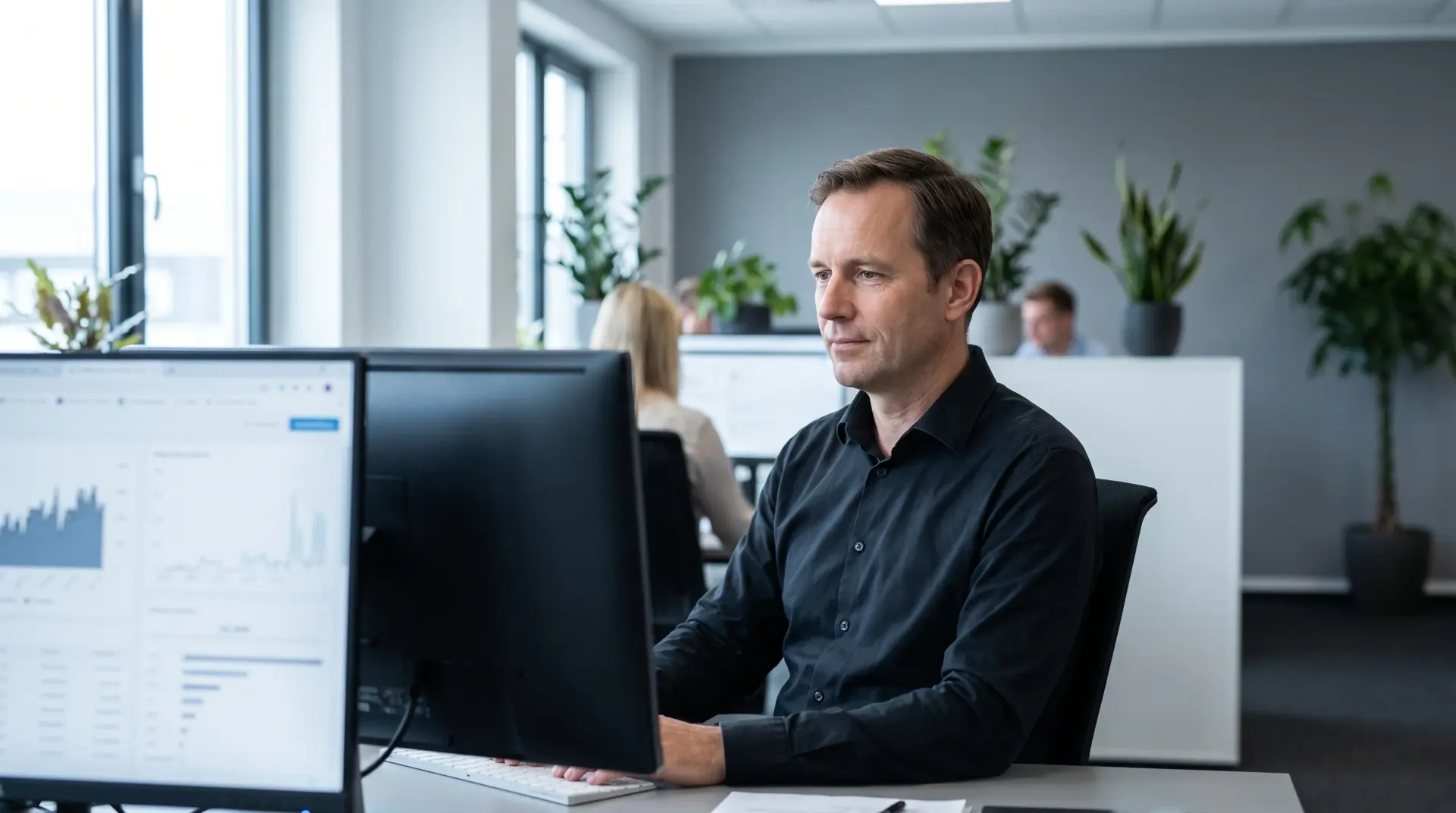 IT-Verantwortlicher eines Mittelstandsunternehmens am Arbeitsplatz mit zwei Bildschirmen